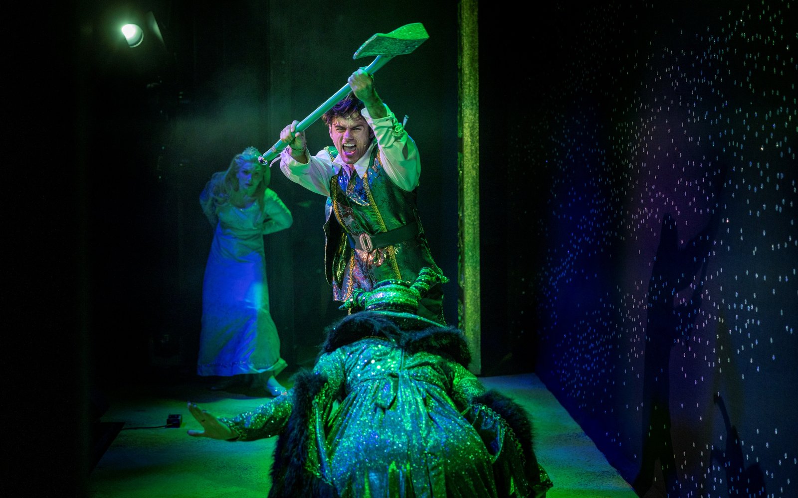 Prince Ken runs at Carabosse, yelling, with his bejewelled axe held above his head. Princess Rose watches, frightened, in the background.