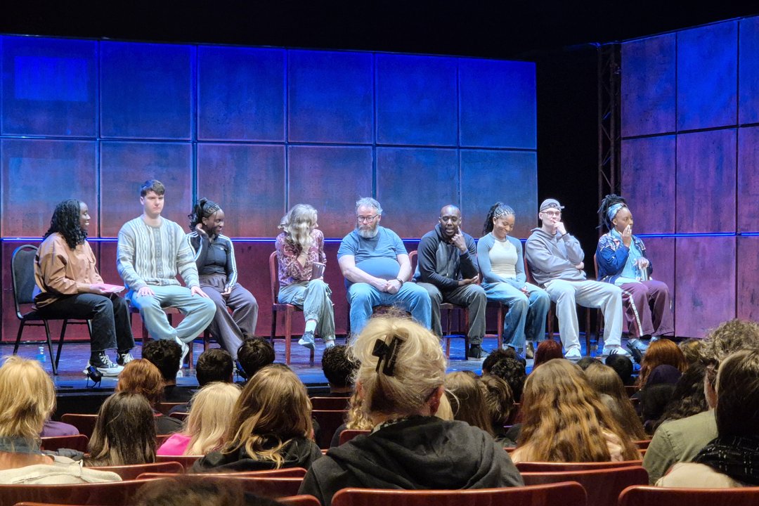 Students participating in a Q&A with the full acting company of Noughts & Crosses on stage at The Arts Theatre Cambridge.