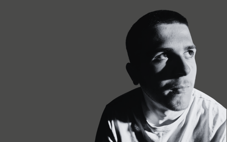 A man in a white tshirt stares off camera wearing a white tshirt