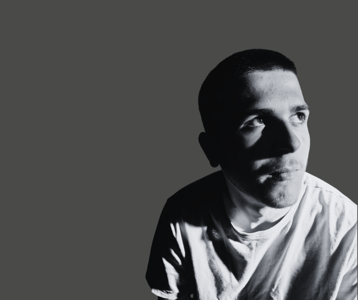 A man in a white tshirt stares off camera wearing a white tshirt