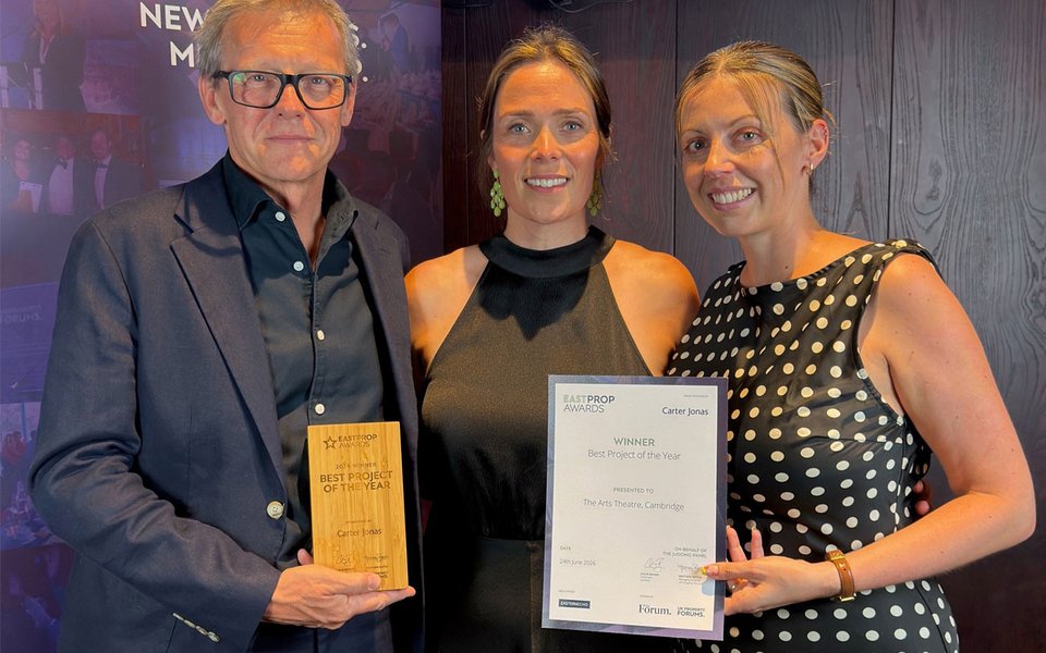 A man and two women standing together holding an award and certificate