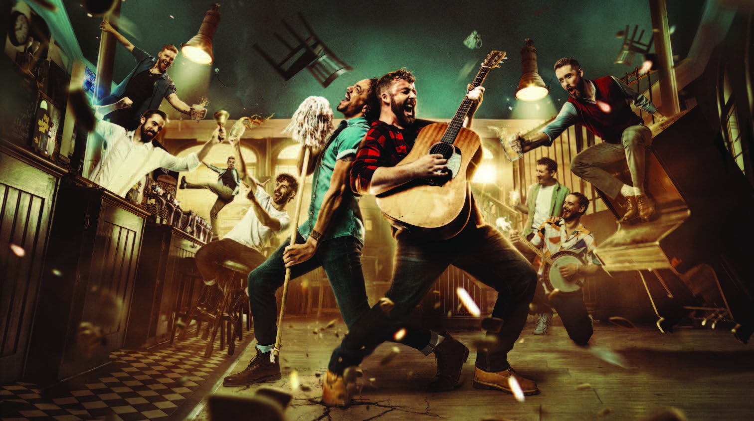 A chaotic scene inside a pub, chairs are flying, the tables and a piano is falling over. A man stands in the middle singing with a guitar.