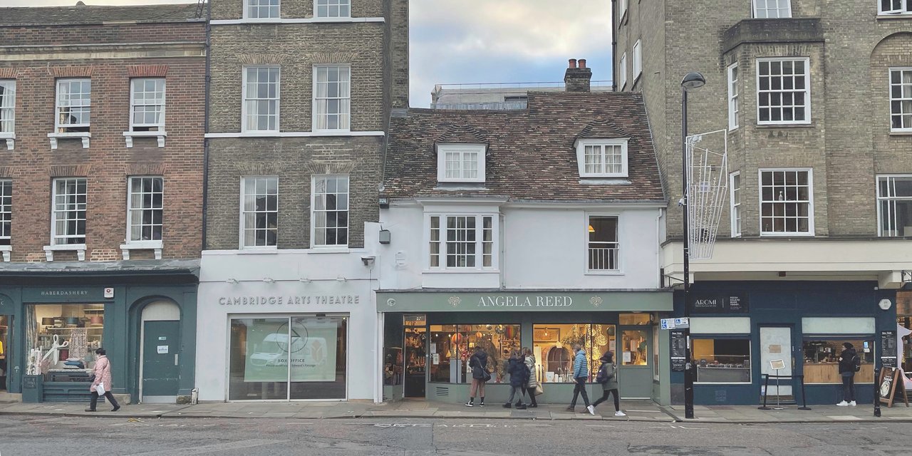 An external photograph of Peas Hill in Cambridge, it shows a row of shops and buildings including The Arts Theatre Cambridge, an antique's shop and a cafe