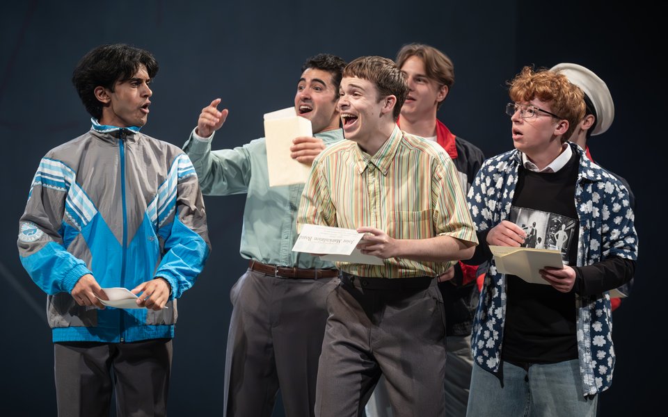A group of young boys laughing, they are holding pieces of paper in their hands