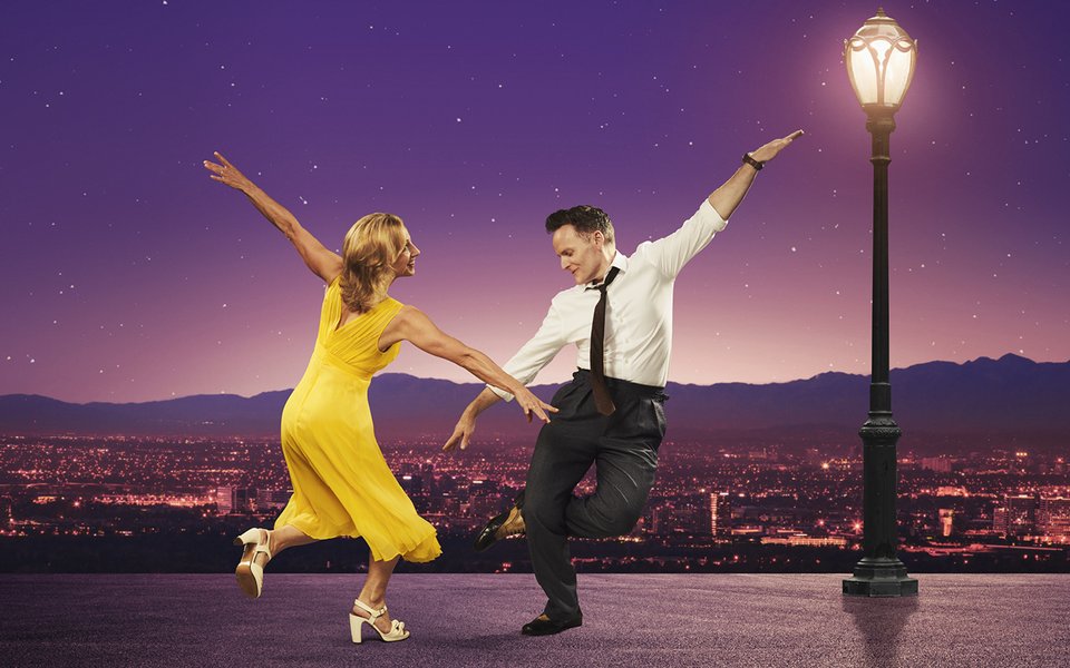A woman in a yellow dress and man dance against a backdrop of Los Angeles
