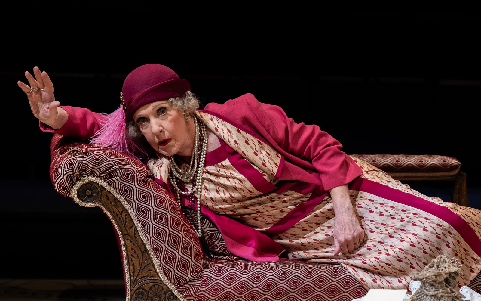 Patricia Hodge, in a pink 1920s outfit, is lying on a chaise longue, looking alarmed.