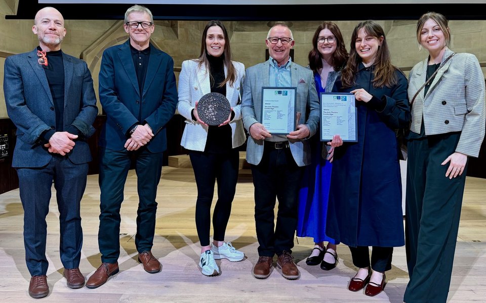 A group of people at an awards ceremony, one of them is holding an award