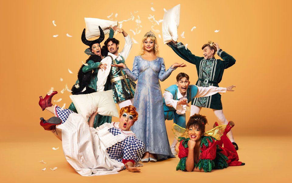 A group of pantomime characters have a chaotic pillow fight, feathers and pillows are being thrown