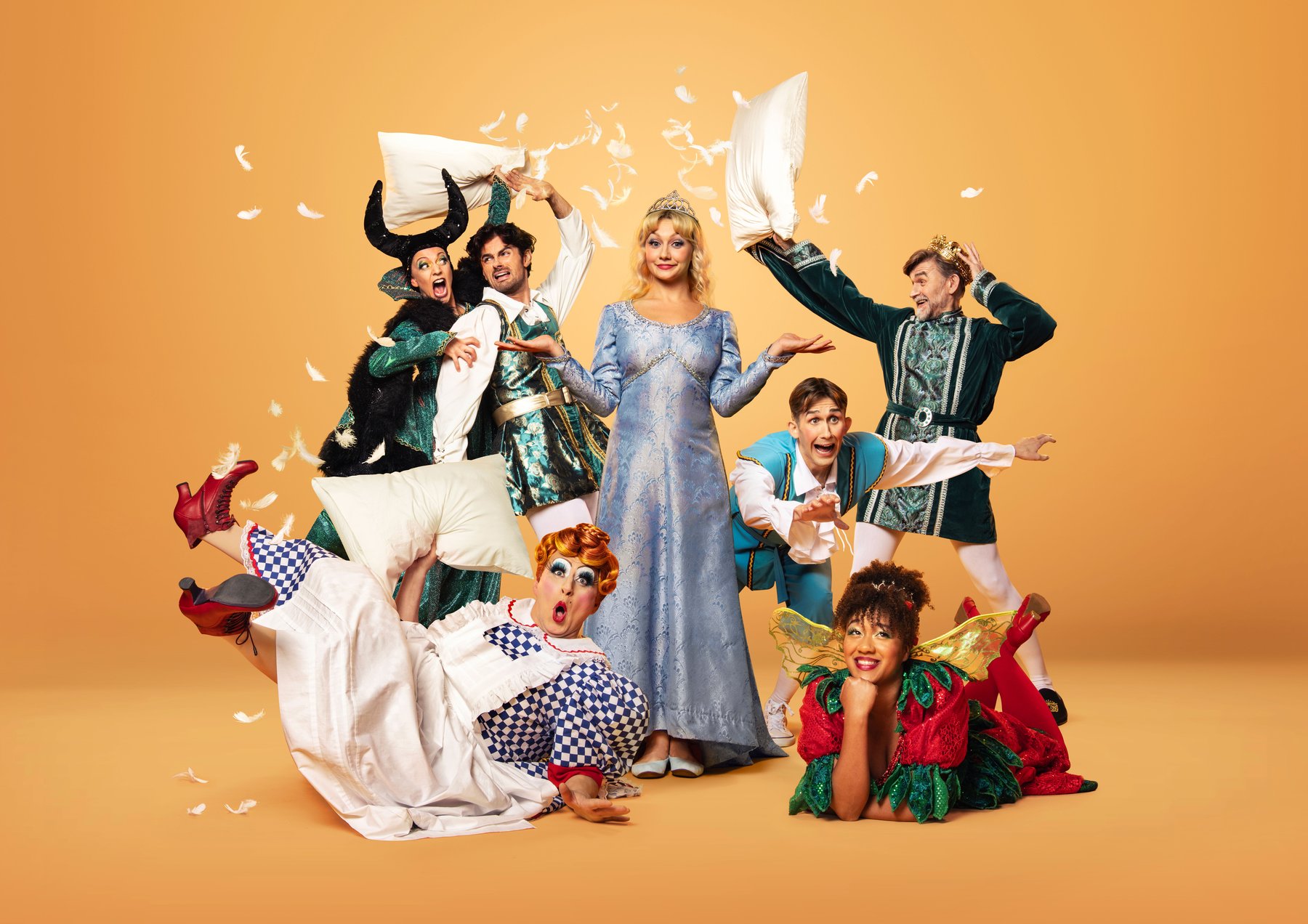 A group of pantomime characters have a chaotic pillow fight, feathers and pillows are being thrown