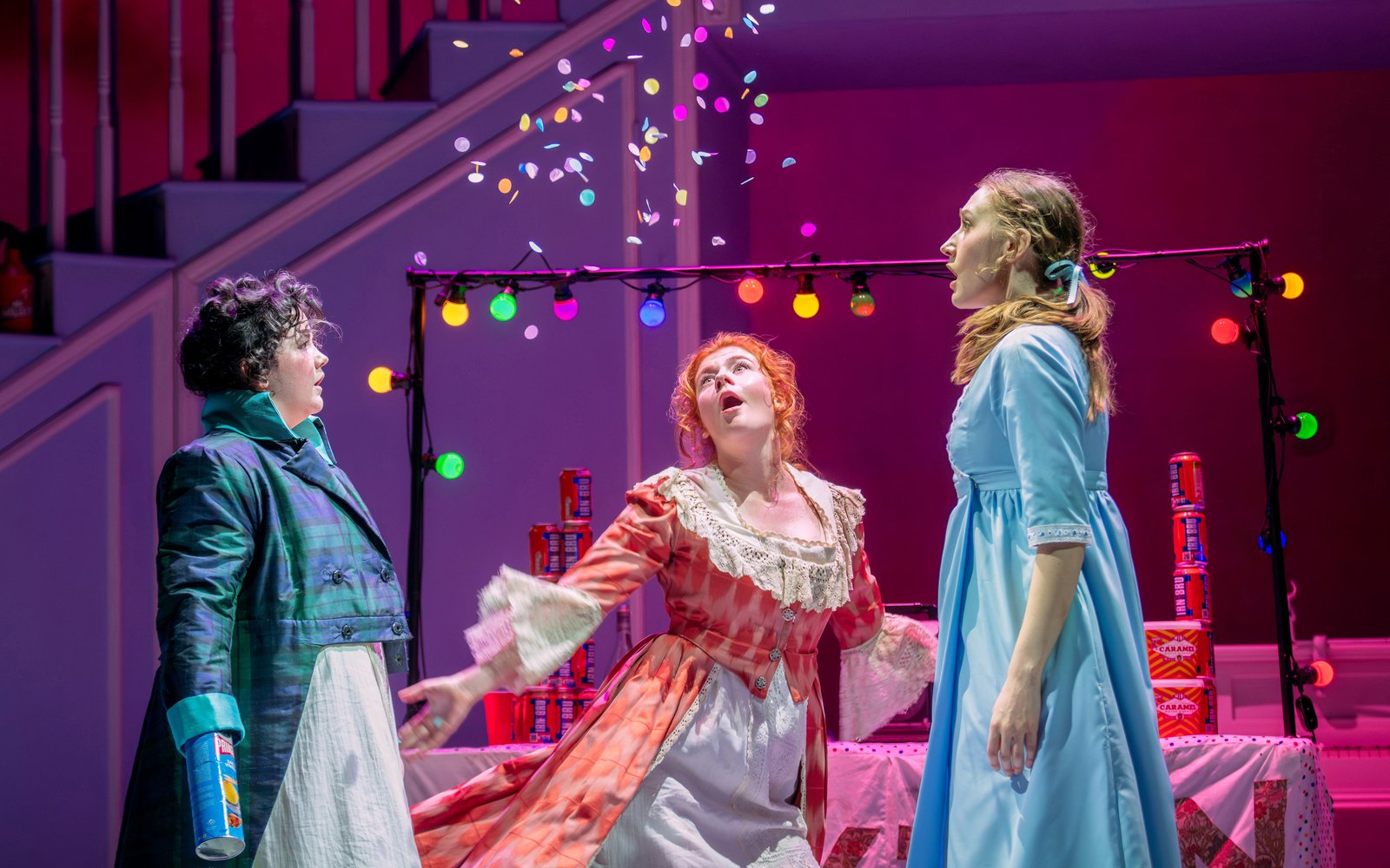 Three women look into the air as colourful confetti falls above them