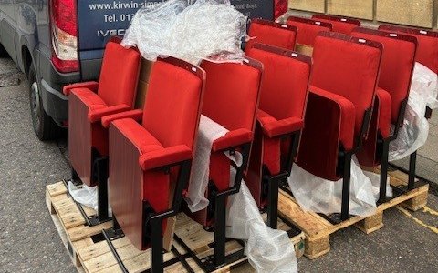 A collection of red theatre seats in front of a van