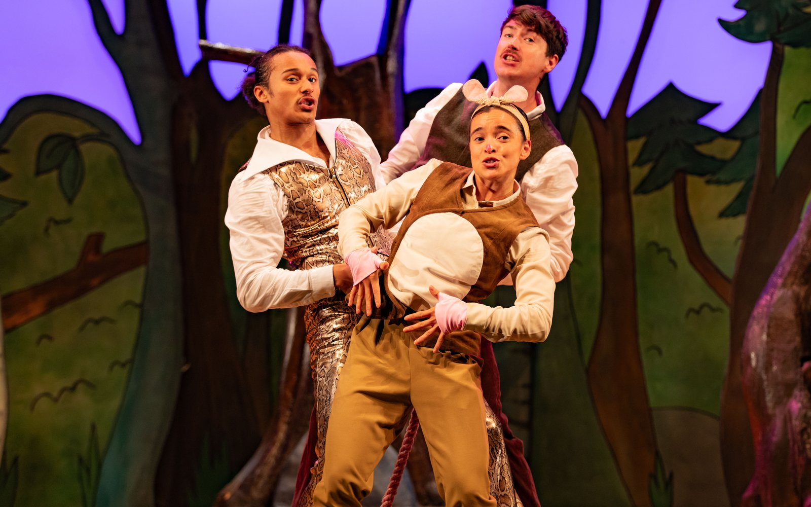 Two men and a woman dance together, they are wearing shirts and waistcoats and the woman has mouse ears on her head