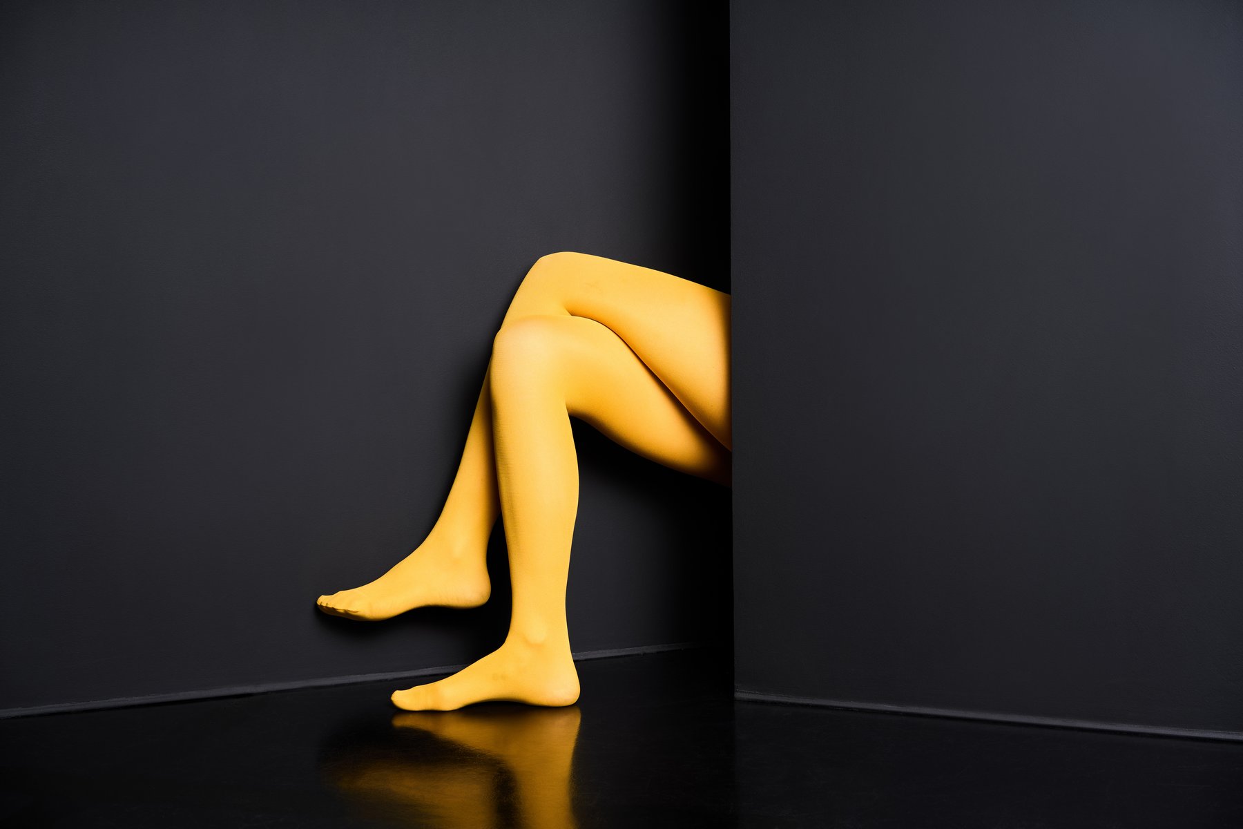 A pair of legs in yellow tights against a black background