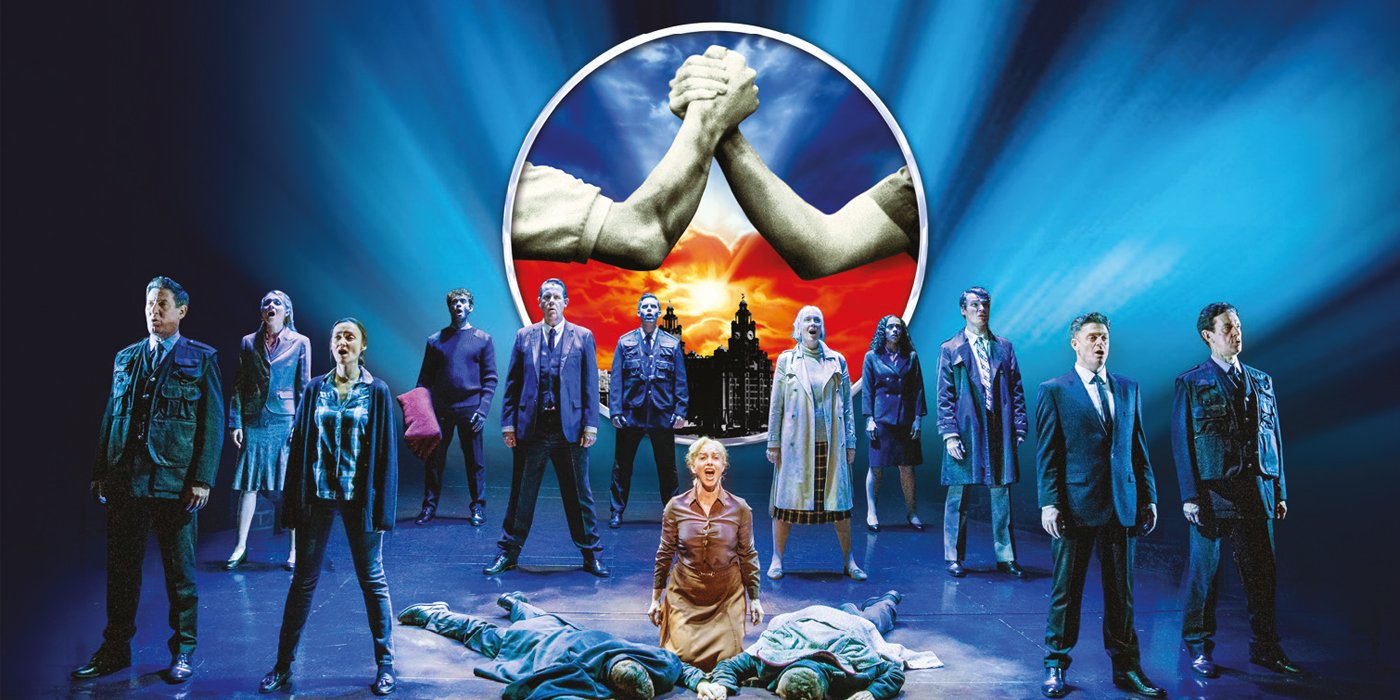 A stage with a group of people standing on it. At the front of the stage there are two boys on the ground and their mother stands over them.